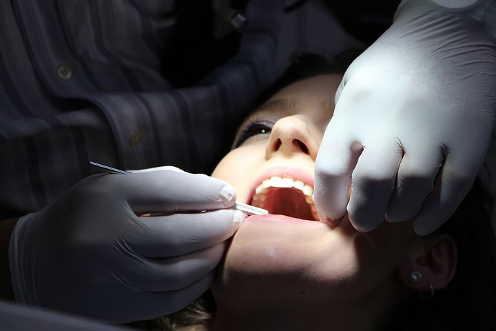 woman's mouth being checked by a dentist